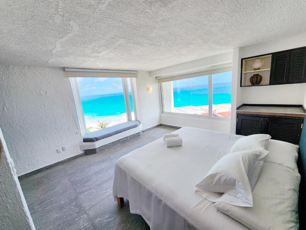a bedroom with a white bed with a view of the ocean at Rodero by Solymar Beach Front Condos in Hotel Zone in Cancún