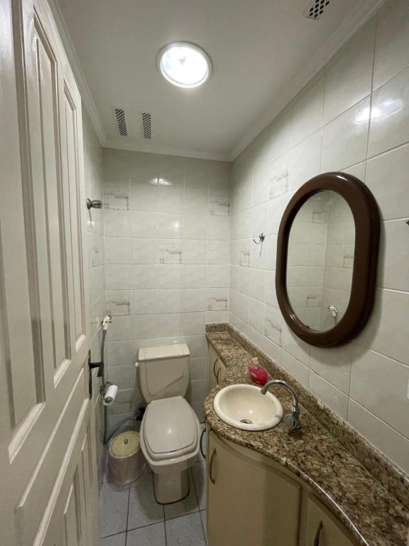 een badkamer met een toilet, een wastafel en een spiegel bij Apto 2 quadras da praia completo in Guarujá