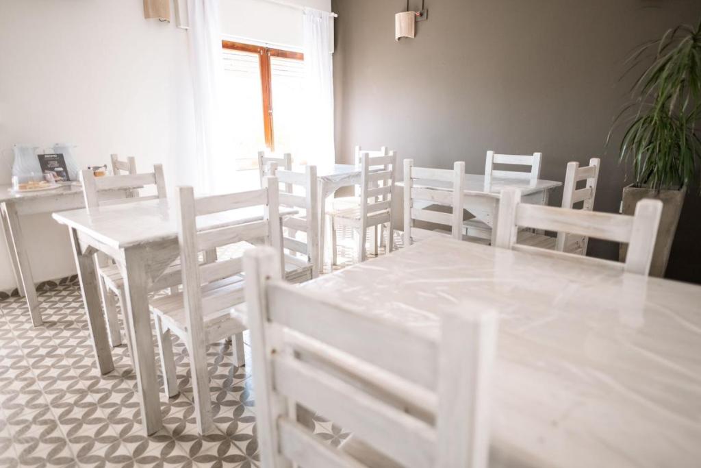 un comedor con mesas blancas y sillas blancas en American Hoteles en Villa Carlos Paz