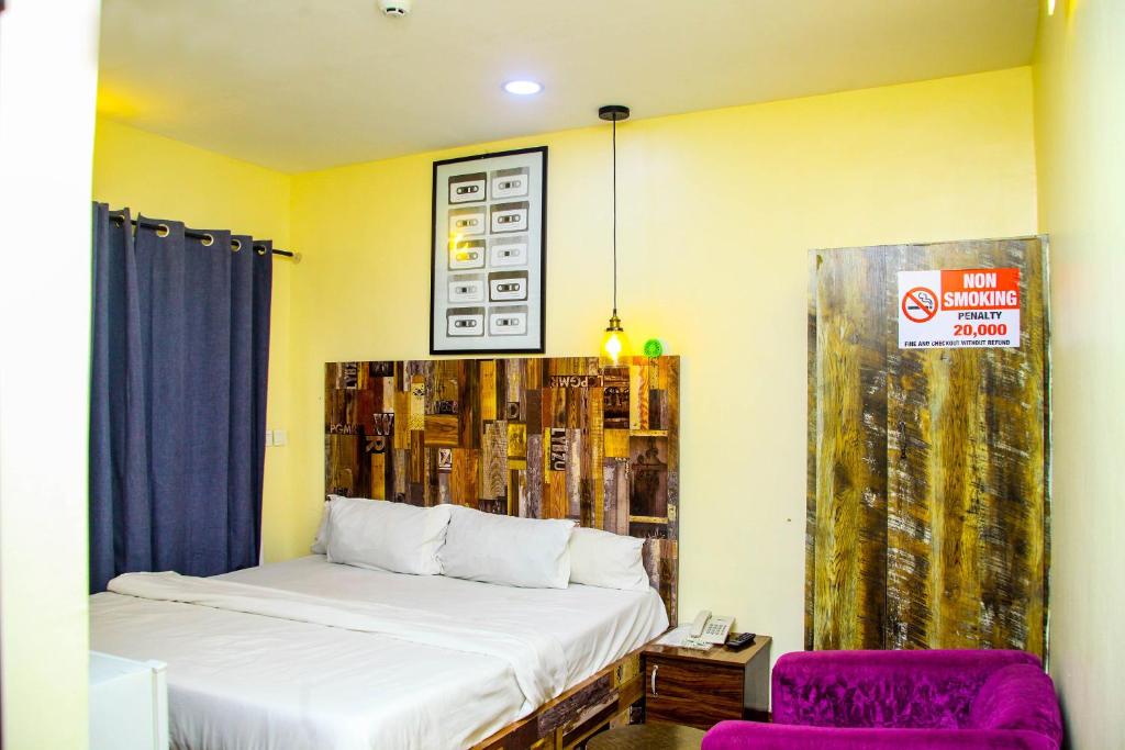 a bedroom with a bed and a purple chair at ONTARIO SUITES in Lagos