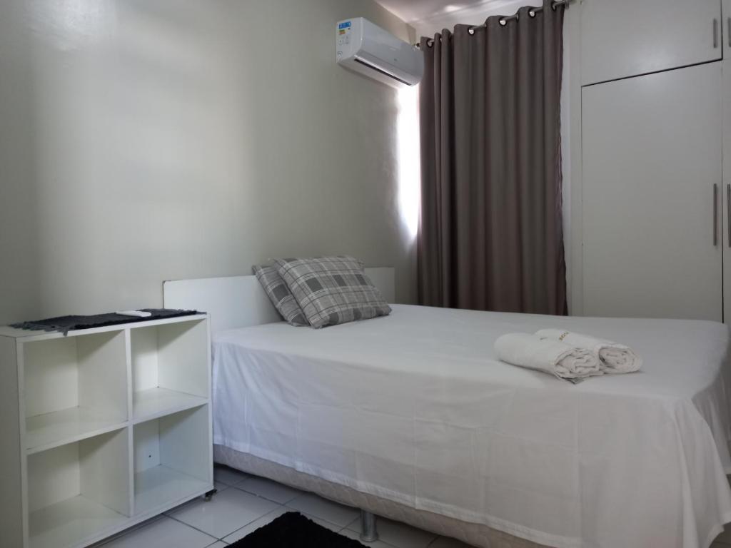 a white bedroom with a white bed and a window at Residencial André Reis in Fortaleza