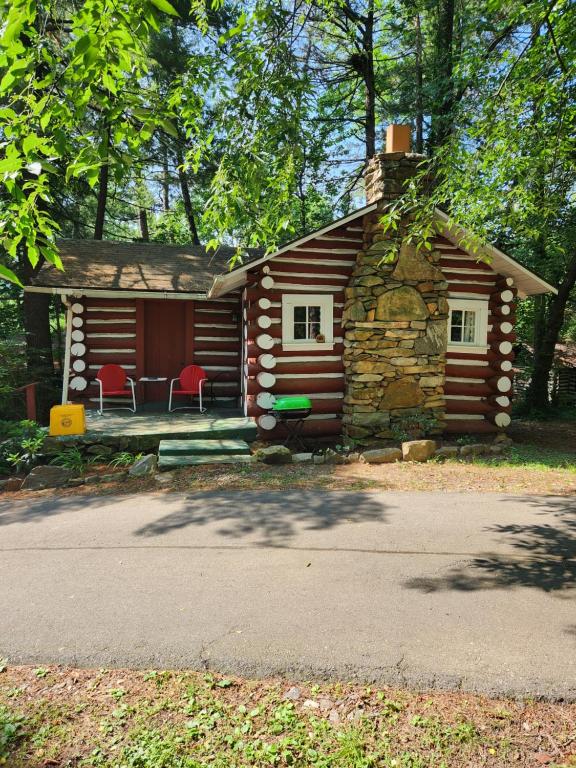 una cabaña de madera con sillas rojas delante en The Pines Cottages, en Asheville