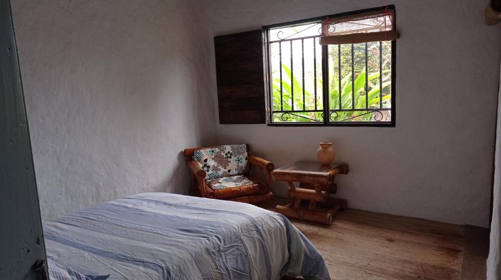 a bedroom with a bed and a chair and a window at Pinar del Rio Eco Habitación Madera in San Agustín