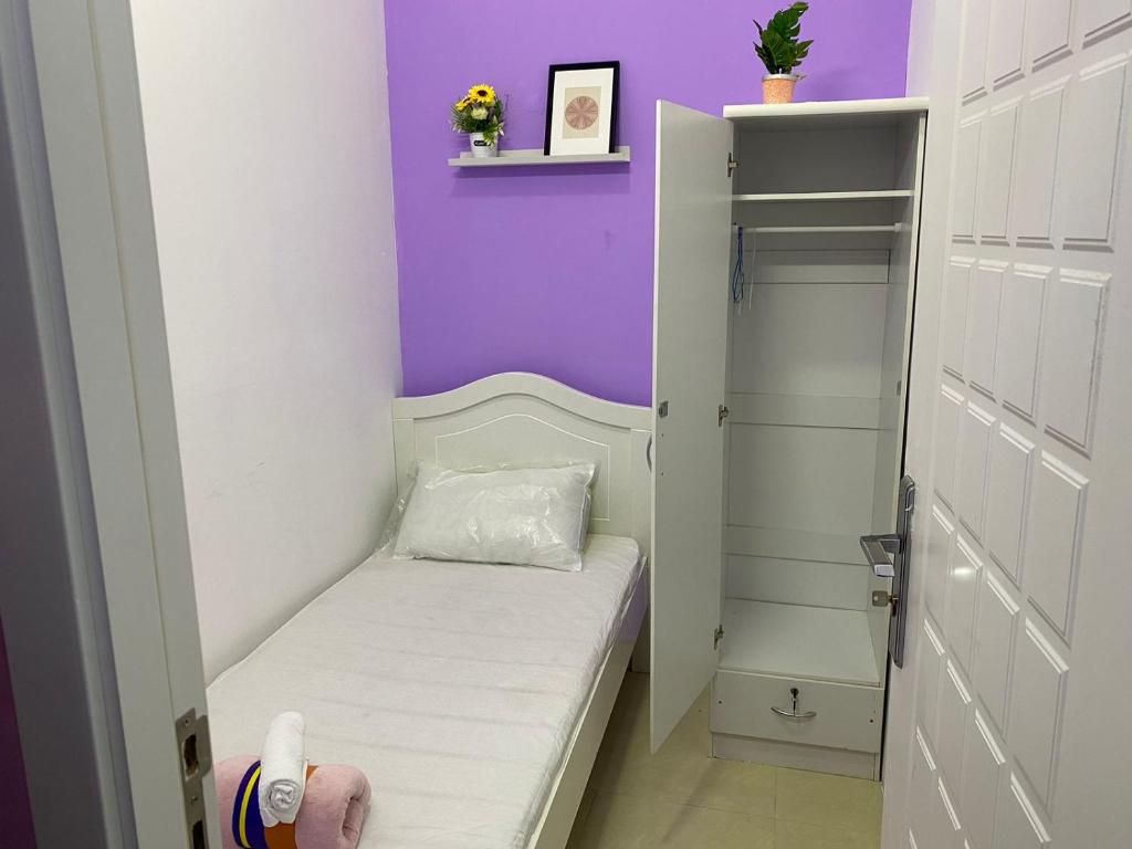 Habitación pequeña con cama y pared púrpura. en Single Partition Room in Al Barsha 1 Near Mashreq Metro, en Dubái