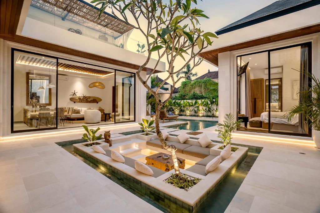 ein Wohnzimmer im Freien mit einem Baum in der Mitte in der Unterkunft Priviere Luxury Villa - Canggu in Canggu