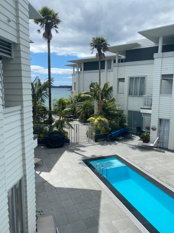 a house with a swimming pool and palm trees at Waterfront 209 in Paihia