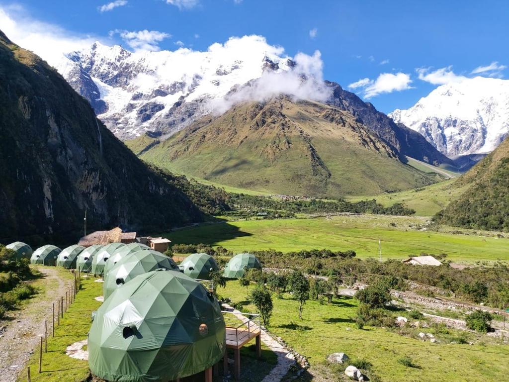 un groupe de tentes dans un champ avec une montagne dans l'établissement Sky Lodge Domes Salkantay, à Soray