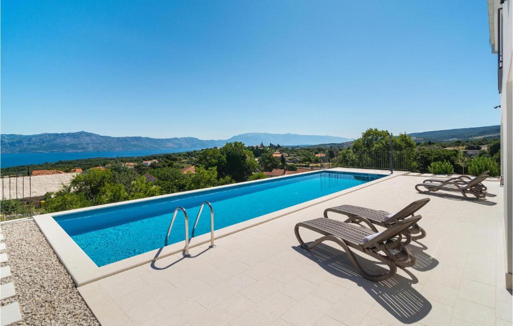 een zwembad met 2 ligstoelen op een patio bij Beautiful Home In Supetar Brac With Outdoor Swimming Pool in Škrip