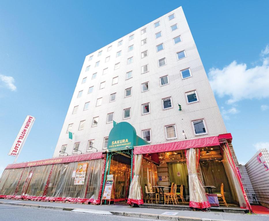 Sakura Hotel Ikebukuro في طوكيو: مبنى أبيض طويل مع طاولات أمامه