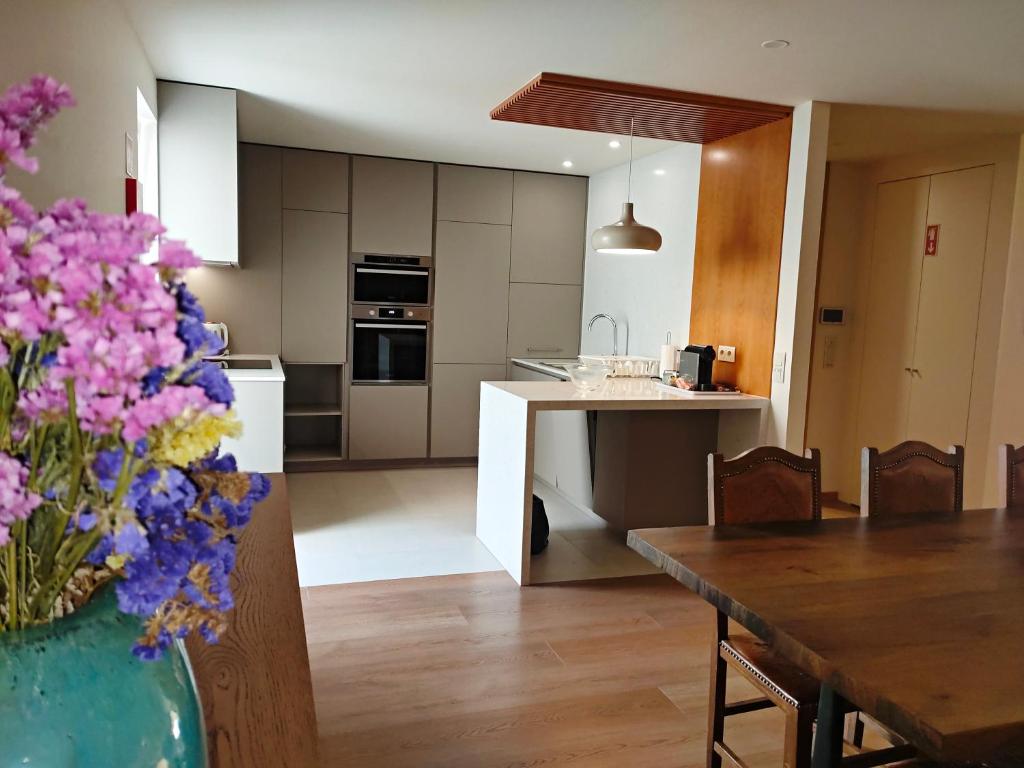 a kitchen and dining room with a table and flowers in a vase at BUTEKO HOUSE AL in Miranda do Douro