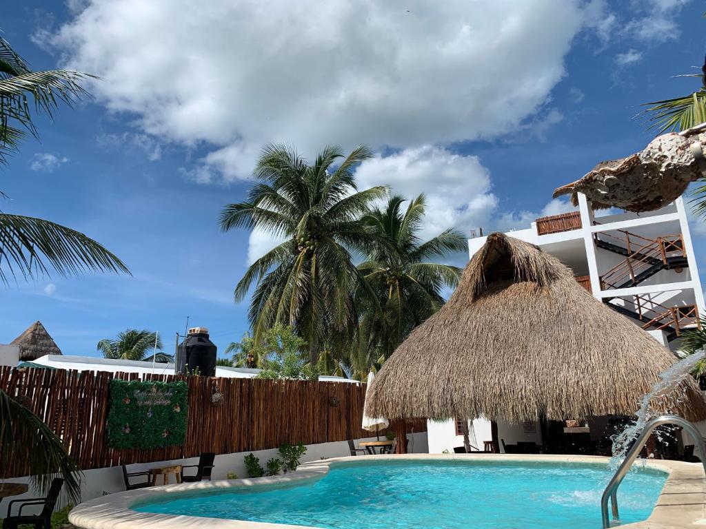 una piscina con sombrilla y palmeras en CASA DELFINES RIO LAGARTOS, en Río Lagartos