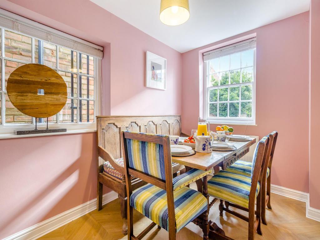 a dining room with pink walls and a wooden table and chairs at Abbots Retreat -uk40757 in Barrow upon Humber