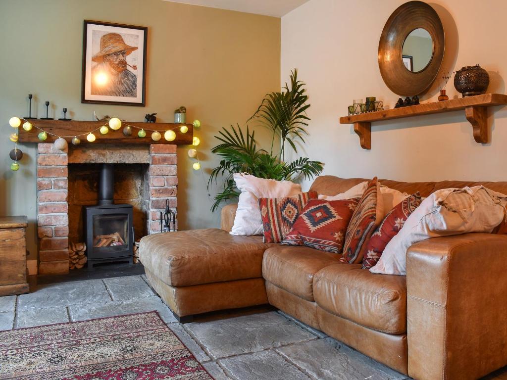 - un salon avec un canapé en cuir brun et une cheminée dans l'établissement Kilaine Cottage, à Loftus