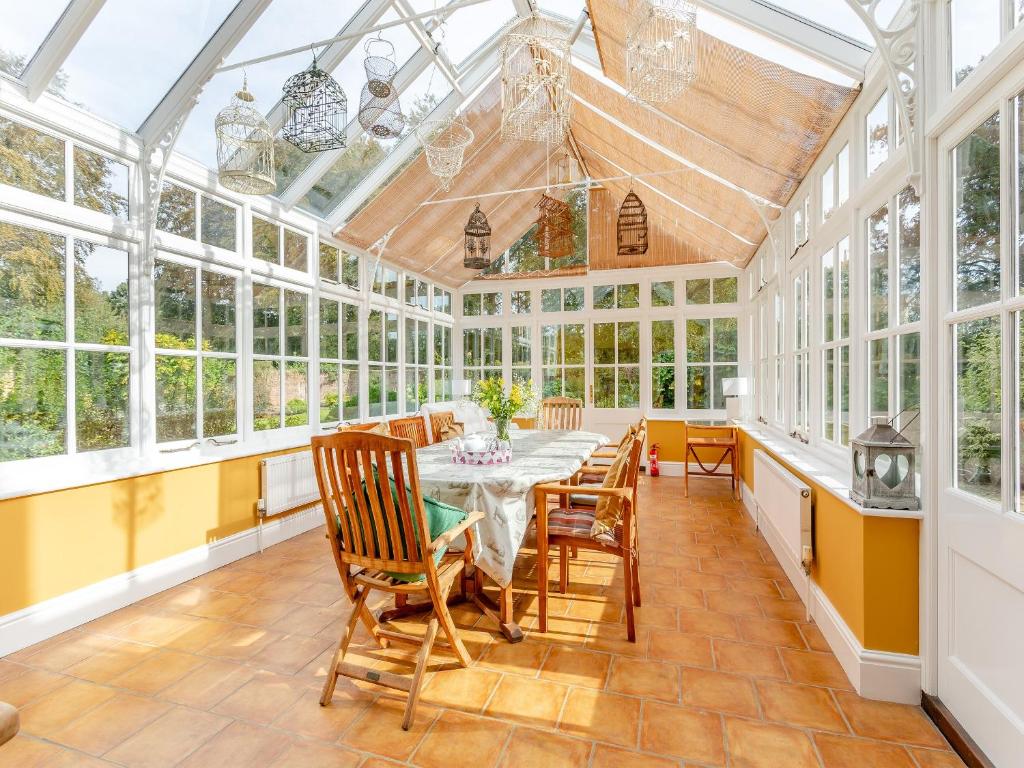 a conservatory with a table and chairs and windows at Manor Farm House - Uk45276 in Sculthorpe