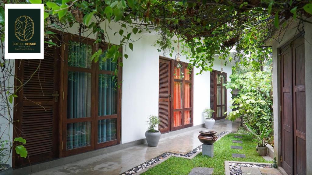 uma vista exterior de uma casa com portas e plantas em Coffee Shade em Midigama East