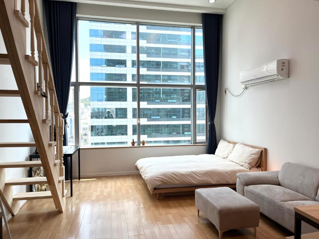 ein Wohnzimmer mit einem Bett und einem großen Fenster in der Unterkunft Hongdae Station loft apartment in Seoul