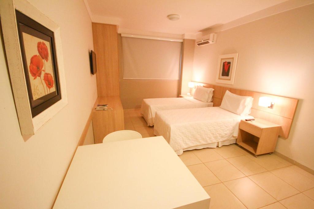 um quarto de hotel com duas camas e uma mesa em Gales Park Hotel em Dourados