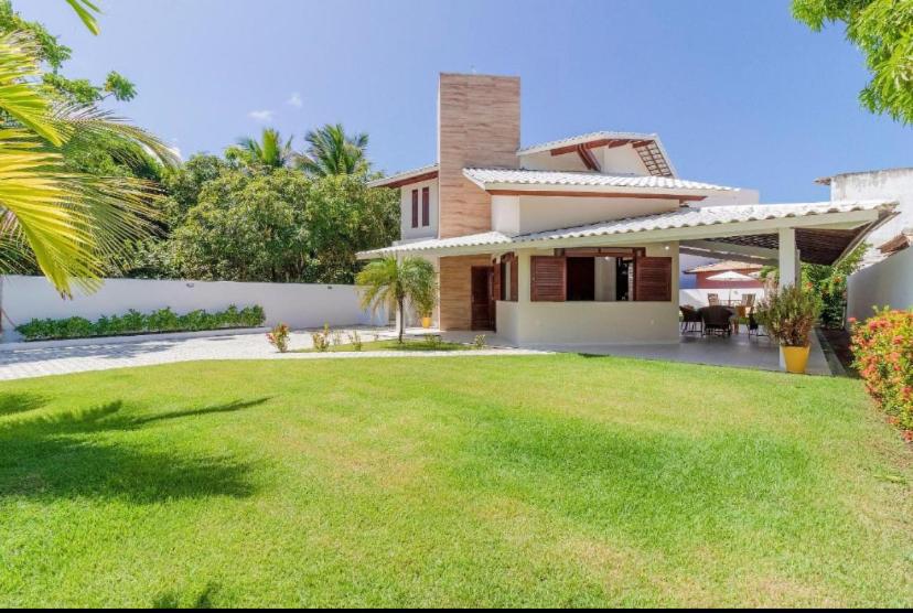 dom z trawnikiem przed nim w obiekcie Guarajuba - casa em condomínio corais a 200 metros da praia w mieście Camaçari