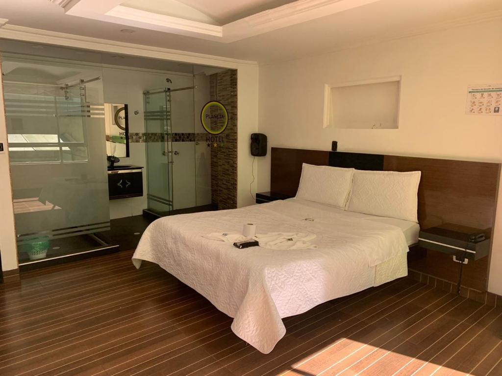 a bedroom with a large bed and a glass shower at Hotel Planeta 3 in Bogotá