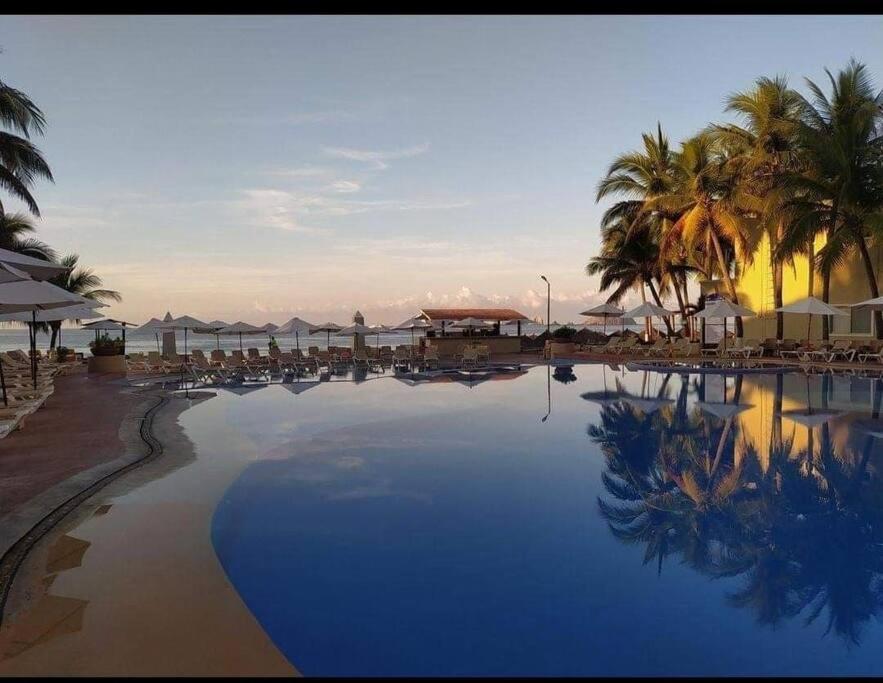 una grande piscina con palme e ombrelloni di departamento en ixtapa 514 a Ixtapa