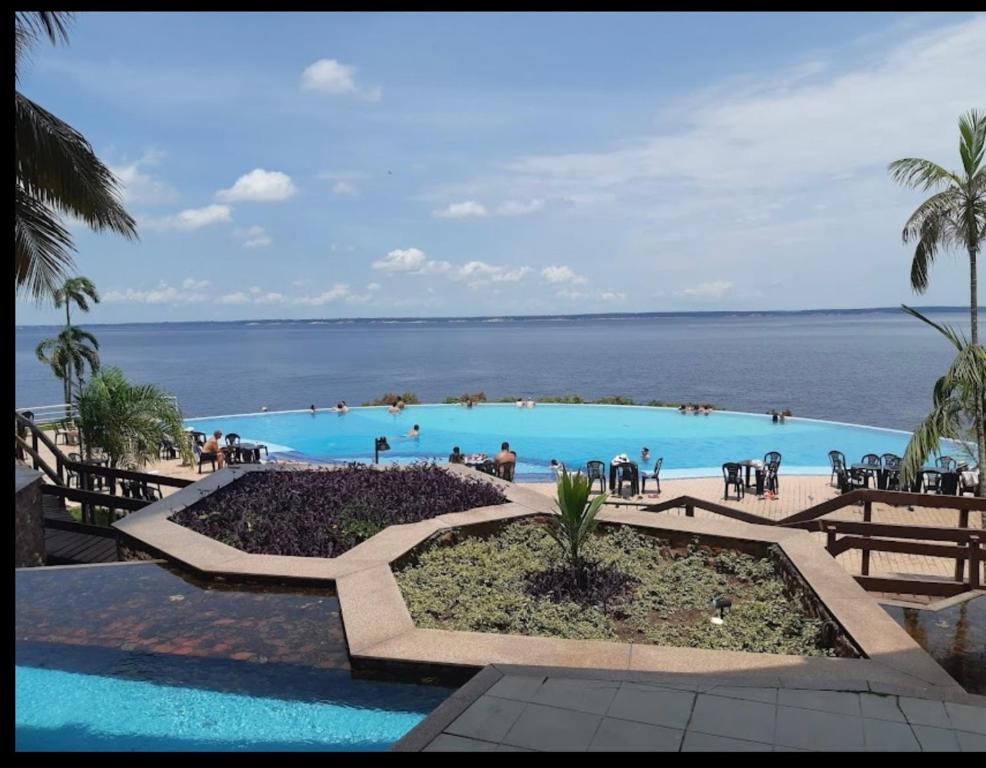 uma grande piscina com o oceano ao fundo em Flat no Condomínio do Edifício Tropical Executive e residence com Vista para o Rio em Manaus
