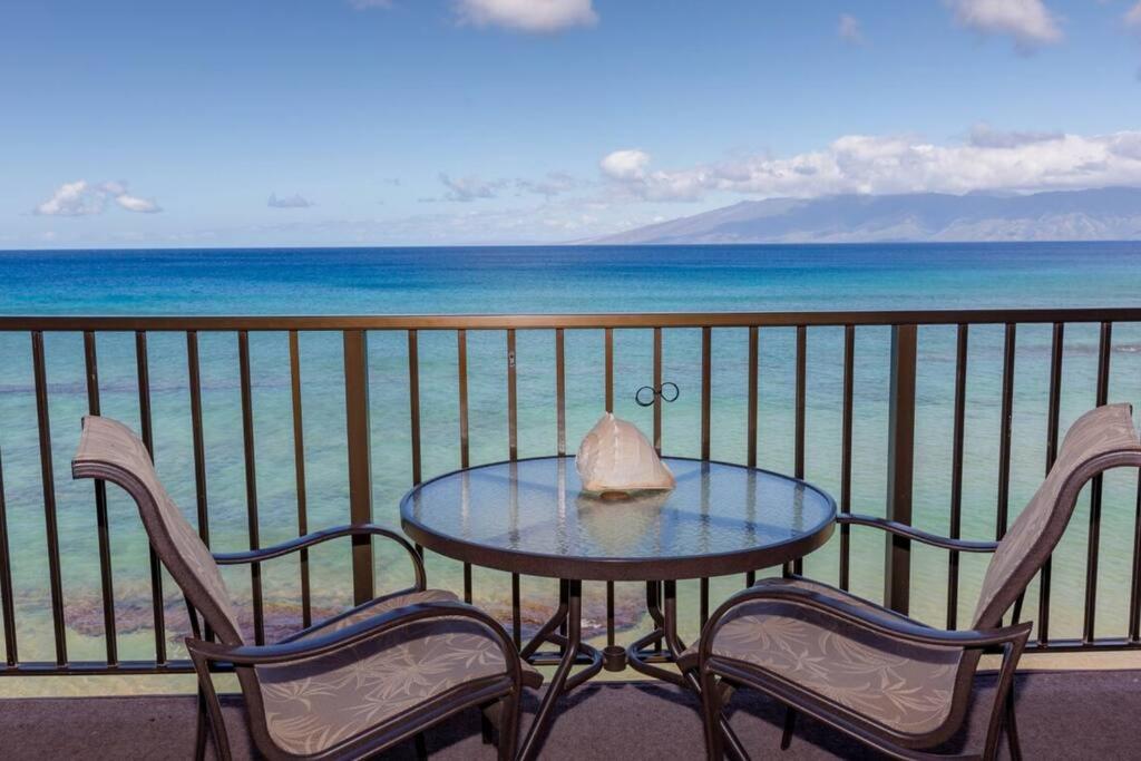 a table and chairs on a balcony with the ocean at Kaleialoha 413- Remodeled Top floor and direct oceanfront views in Kahana