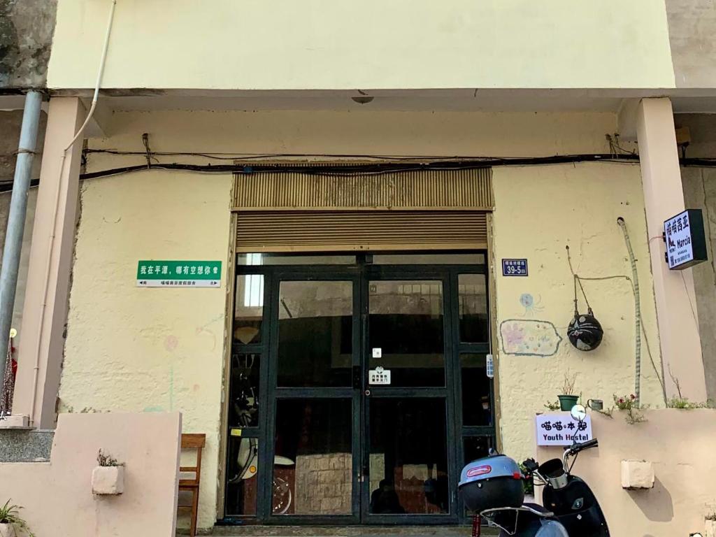 une moto garée devant un immeuble avec une porte dans l'établissement Meow! Marcia Youth Hostel, à Pingtan
