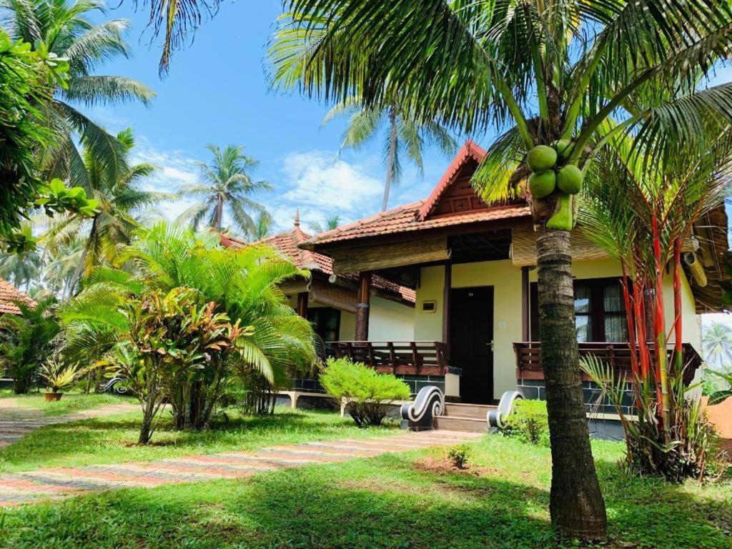 dom z palmą przed nim w obiekcie Maadathil Cottages & Beach Resort w mieście Varkala