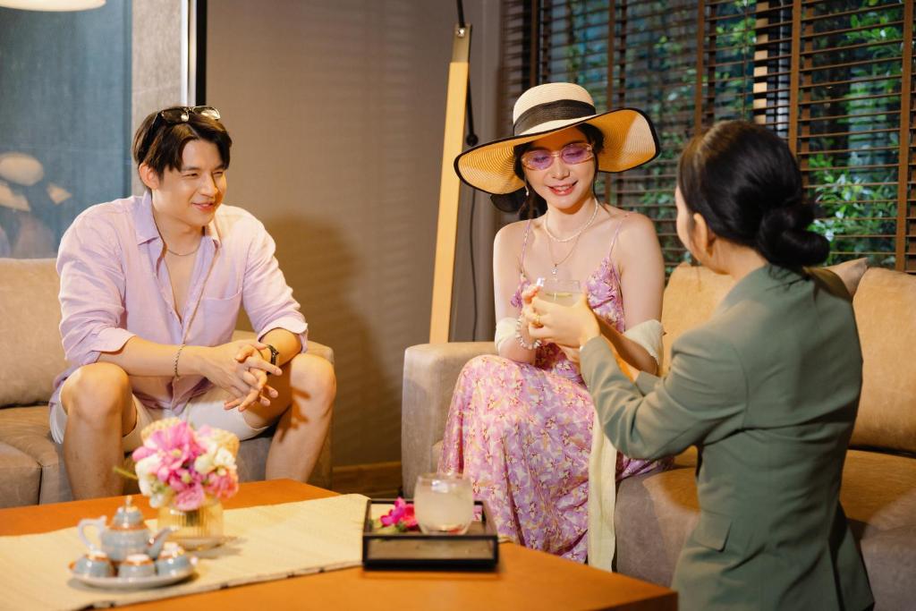 Three guests converse over tea in a warmly furnished hotel lounge.