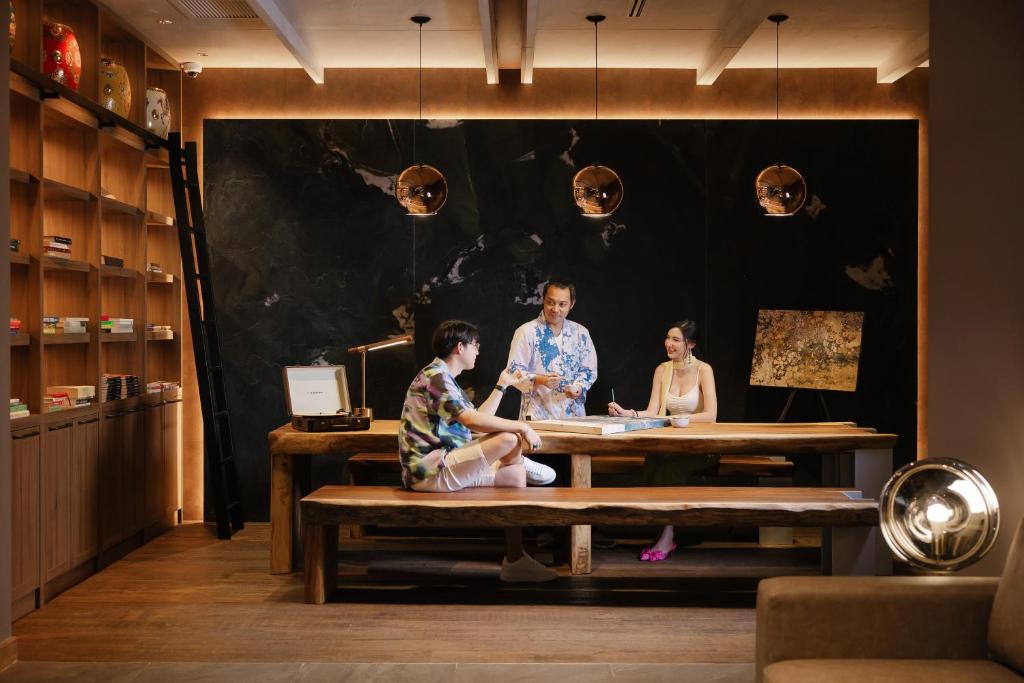 A broad communal lounge combines a long table, library shelving, and lounge seating.