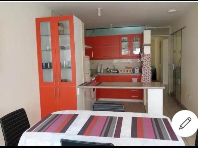 a kitchen with red cabinets and a table and chairs at Espacioso departamento in Lima
