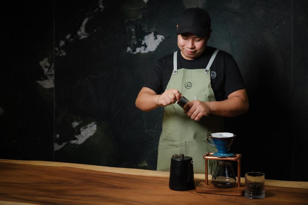 A barista prepares pour-over coffee behind a wooden counter.