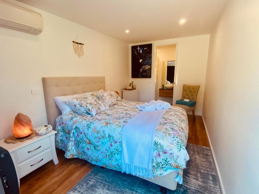 a bedroom with a bed with a blue comforter at Great Ocean Road Wellness and Nature Stay in Apollo Bay