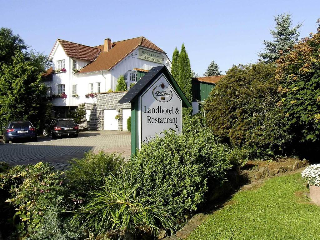 una señal frente a un edificio con una casa en Landhotel-Restaurant Schwalbennest, en Zierenberg