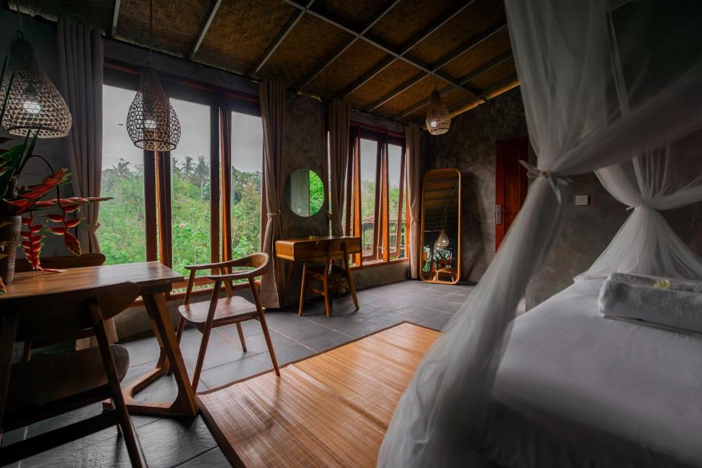 a bedroom with a bed and a desk and a table at Padangan Lodge By Bali Cabin in Padangan