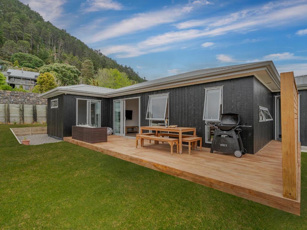 a black tiny house with a deck at A Sunshine Retreat - Pauanui Holiday Home in Pauanui