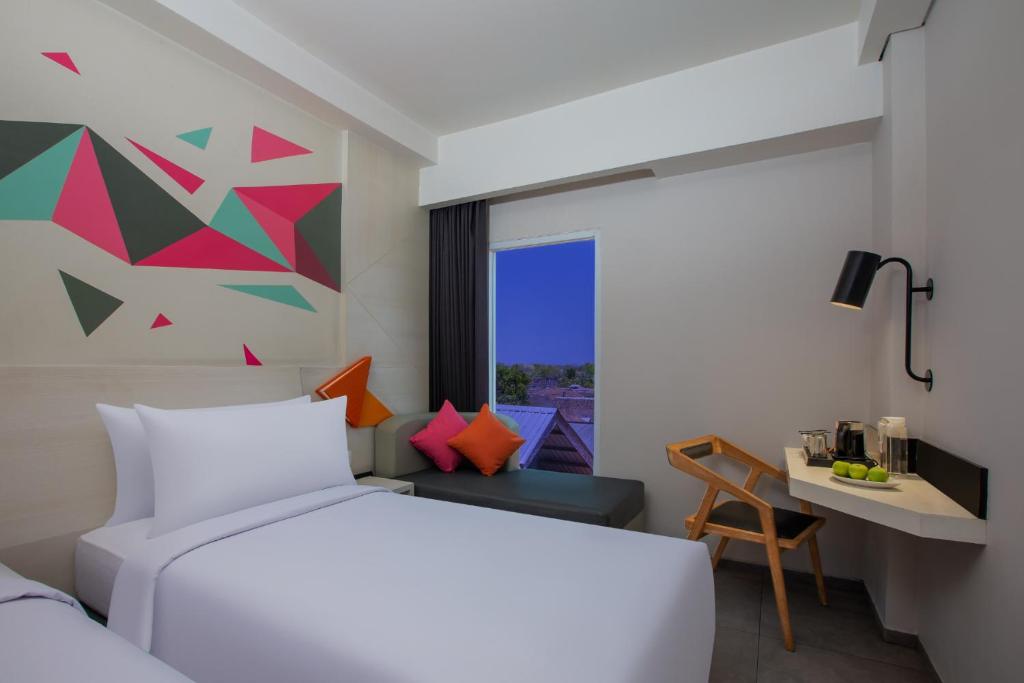 a bedroom with a bed and a desk and a window at favehotel Madiun in Madiun
