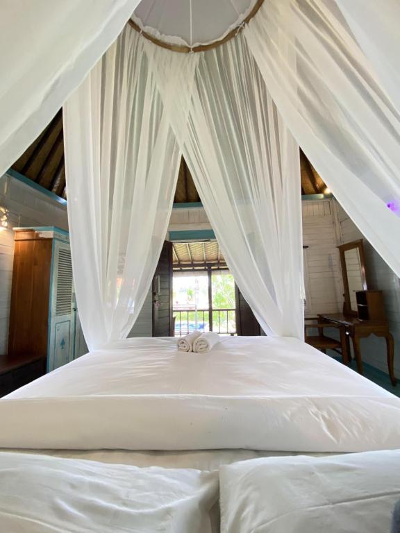 a white bed with white curtains in a room at Kubu Di Omo Villas in Munggu