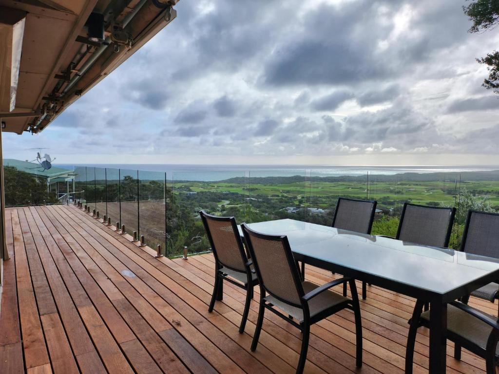 una terraza de madera con mesa y sillas. en Cape Schanck Golf and Ocean Views Holiday Villa, en Cape Schanck