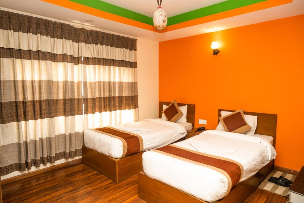 2 Betten in einem Zimmer mit orangefarbenen Wänden in der Unterkunft Kathmandu Peace Hotel in Kathmandu