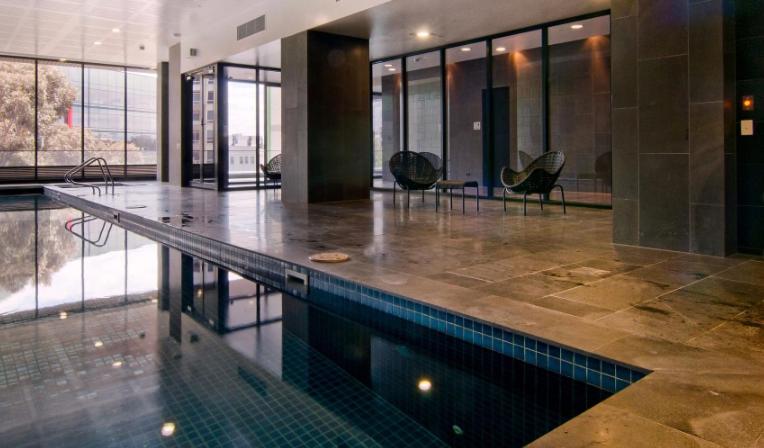 a large swimming pool in a building with chairs at Two bedrooms apartment in the heart of Melb CBD in Melbourne
