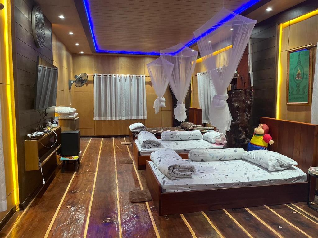 um quarto com quatro camas e uma televisão nele em เฮือนอิสานโฮมสเตย์ 