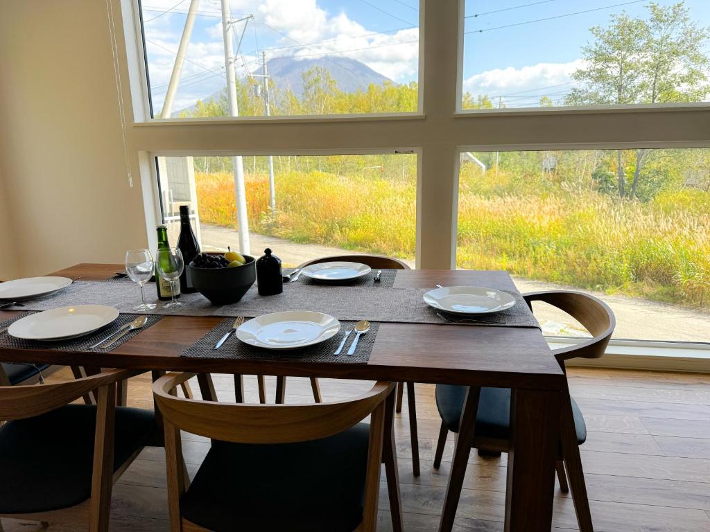 a dining room table with chairs and a large window at Soga House in Kabayama