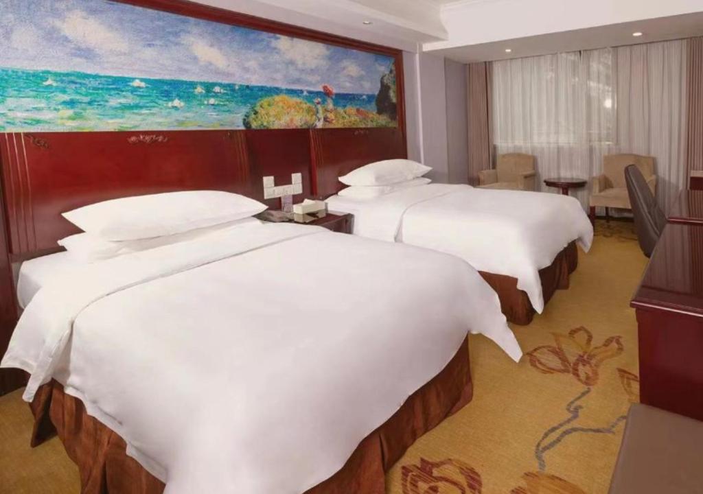 a hotel room with two beds and a painting on the wall at Vienna International Hotel - Shanghai Jiaotong University Humin Road in Shanghai