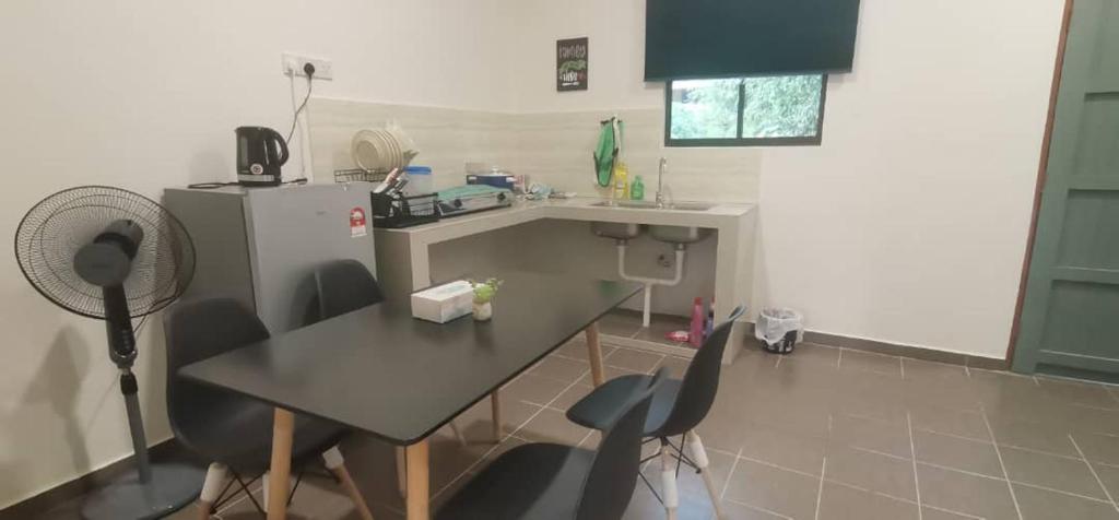 Una cocina con mesa y sillas y un refrigerador. en TEJAH HOMESTAY, en Johor Bahru