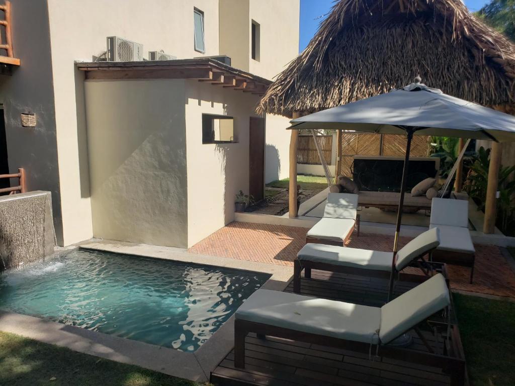 una piscina con sillas y una sombrilla junto a una casa en CASA CANDRA (HOTEL BOUTIQUE), en San Francisco