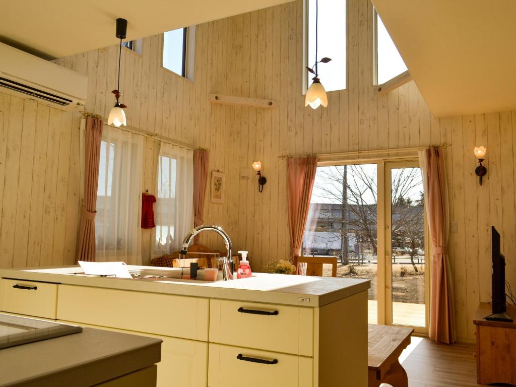 a kitchen with white cabinets and a sink and windows at Tree Village Karuizawa in Karuizawa