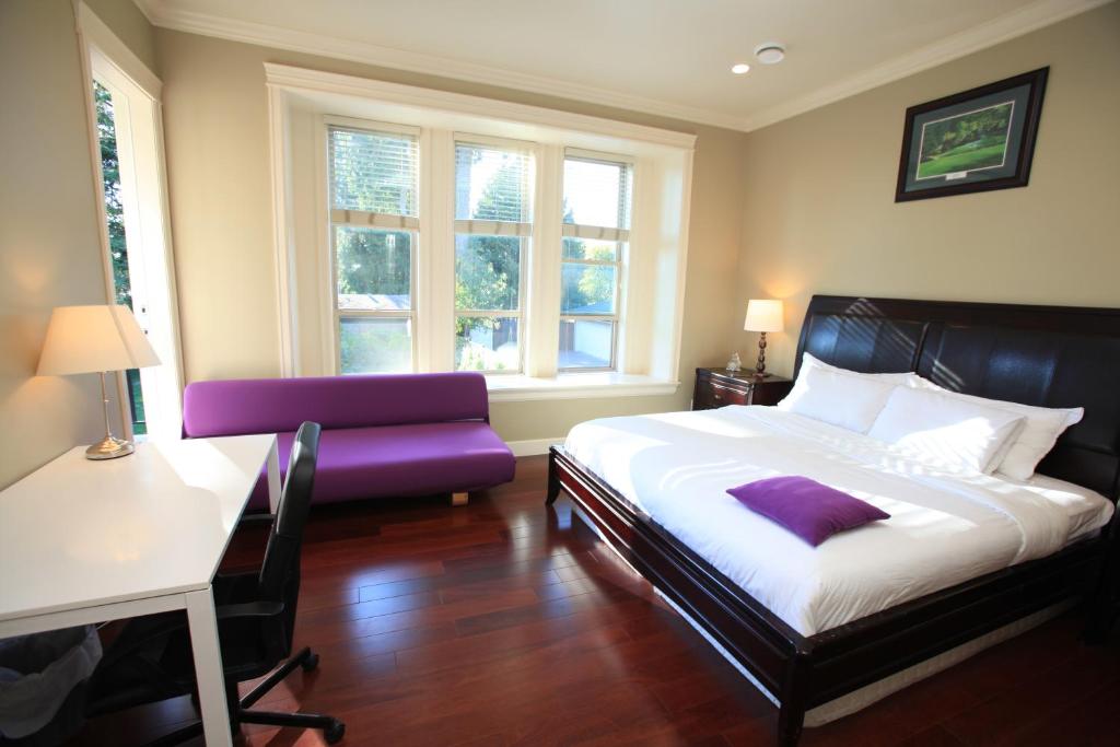 um quarto com uma cama, uma cadeira e janelas em Vancouver Metrotown Guest House 8 mins walk to Sky Train em Burnaby