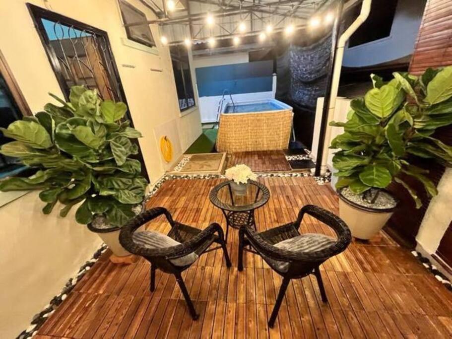 a wooden deck with two chairs and a table and some plants at Modern Family Retreat by STAYco - PS4, Mini-Pool, Pool table - just 5 mins to Beach ! in Ayer Itam
