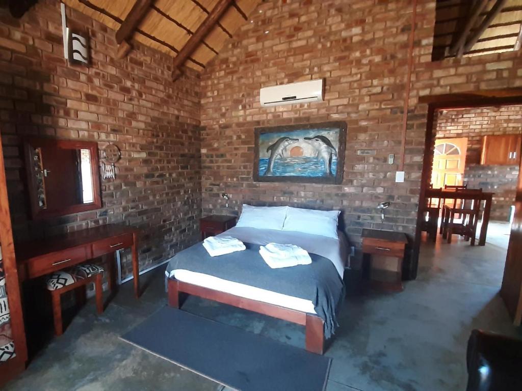 a bedroom with a bed and a brick wall at West Nest Lodge in Gobabis